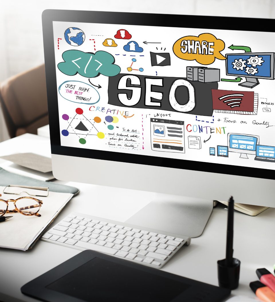 Computer mit digitaler Kunst zu SEO-Konzepten, darunter Diagramme, Grafiken und Symbole für Teilen, Cloud und Technologie. Ein Stifttablett steht nebenan auf dem Schreibtisch, zusammen mit Notizbüchern und einem Laptop.