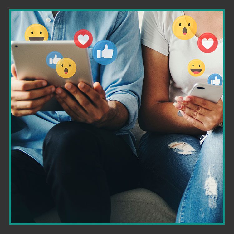 Zwei Personen sitzen zusammen und nutzen ein Tablet und ein Smartphone. Um sie herum schweben verschiedene Social-Media-Reaktionssymbole wie Daumen hoch, Herz und überraschtes Gesicht und suggerieren Online-Interaktion und Engagement.